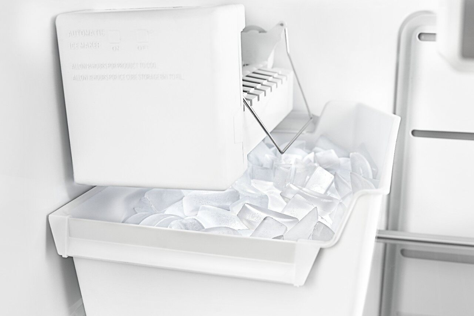 White ice maker inside freezer compartment with full ice bin