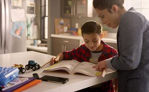 Woman helping a child with homework at a kitchen island