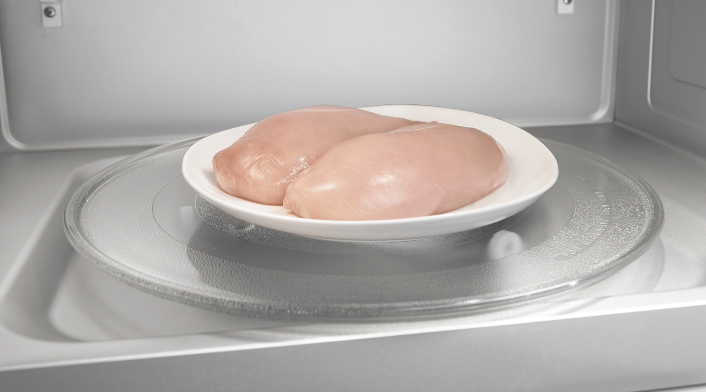 Two chicken breasts on a plate in a microwave