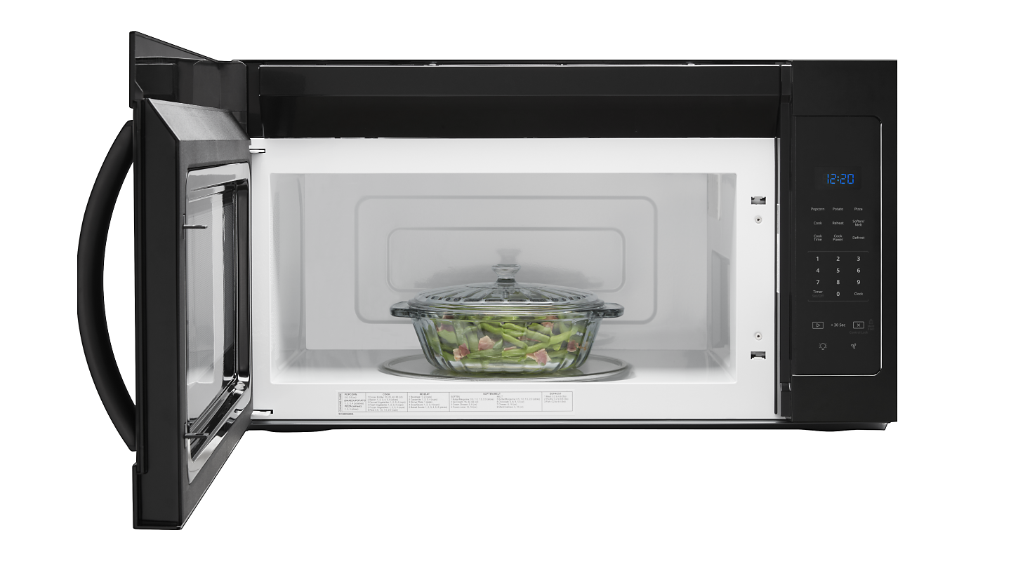 A glass container with meat and vegetables in a microwave