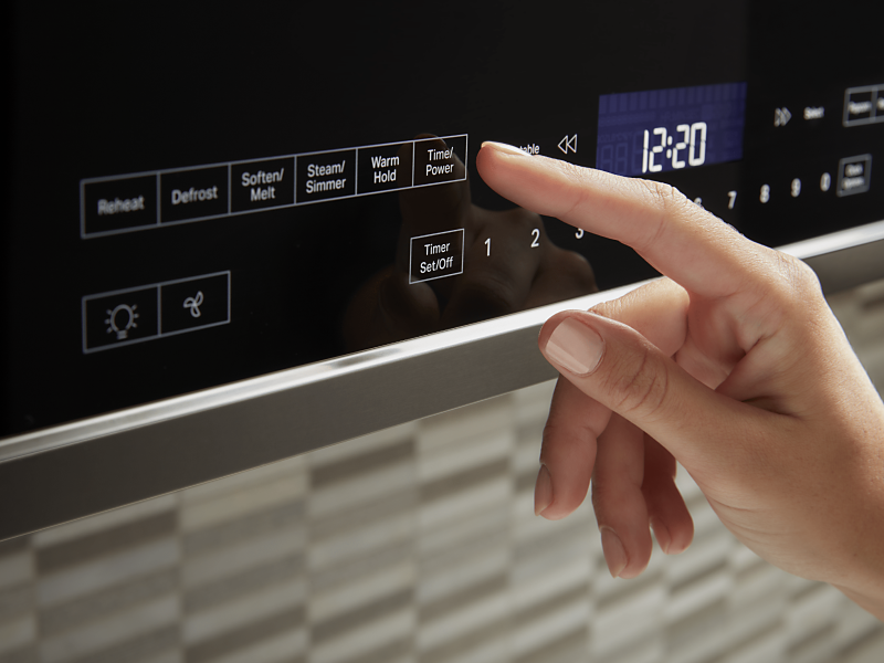 A person selects a microwave setting from a control panel