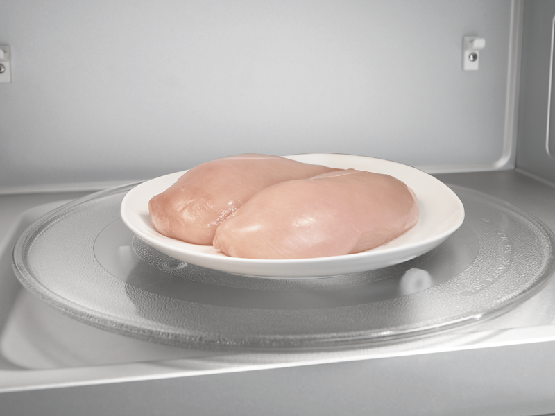 Two chicken breasts on a plate in a microwave