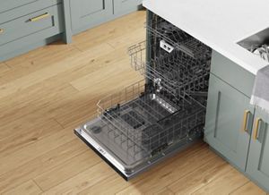 Angled overhead view of an open dishwasher with racks pulled out in a green kitchen