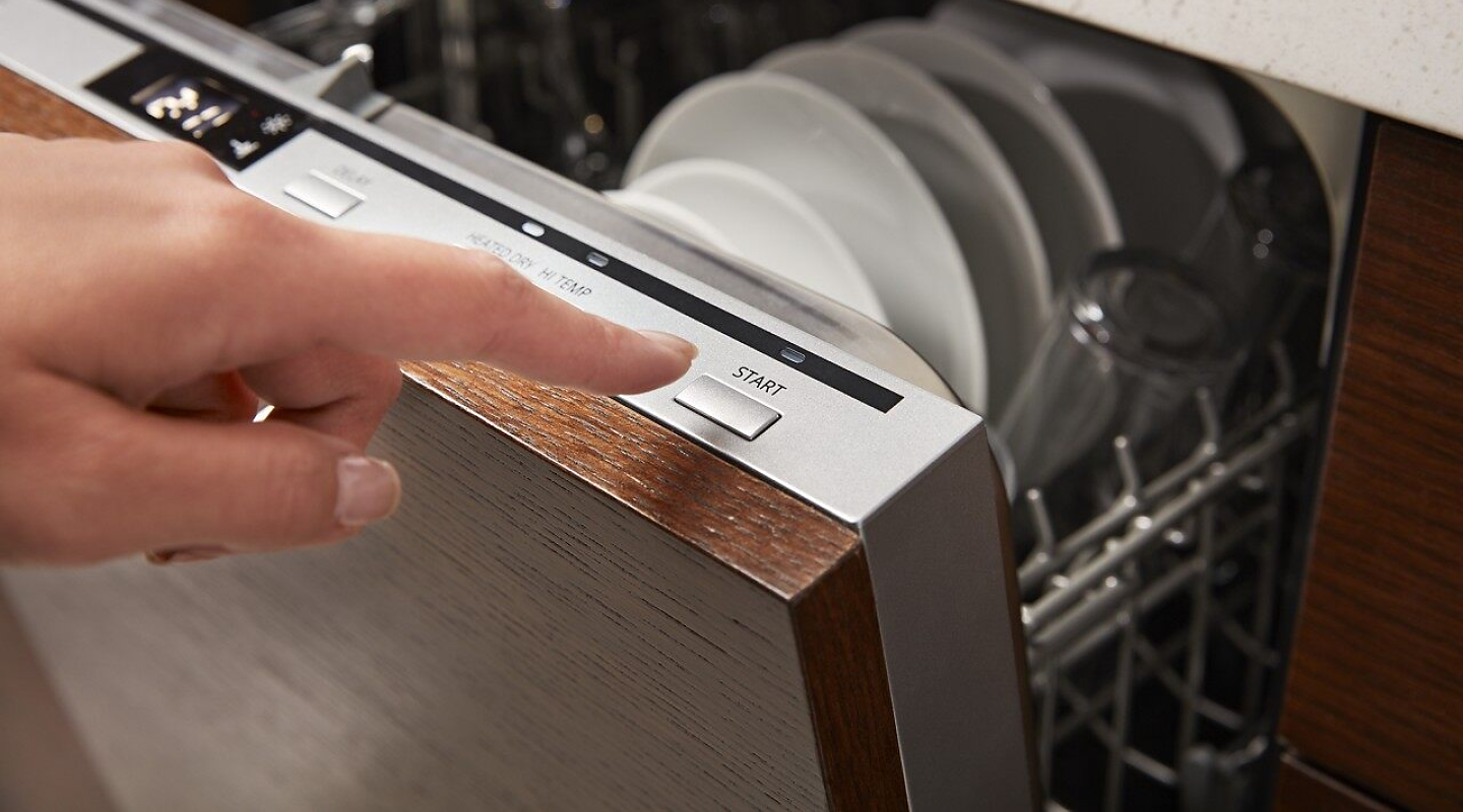 A closeup of a person programming a wash cycle on a Whirlpool® dishwasher.