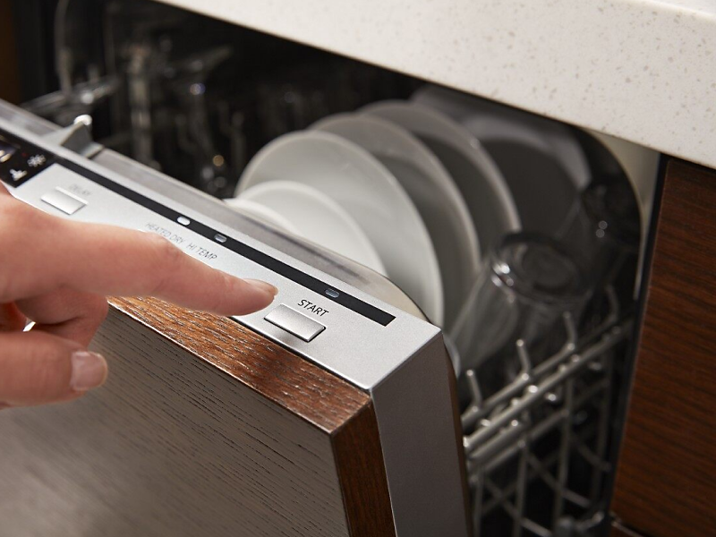 A closeup of a person programming a wash cycle on a Whirlpool® dishwasher.