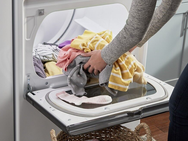 Person loading laundry into a dryer