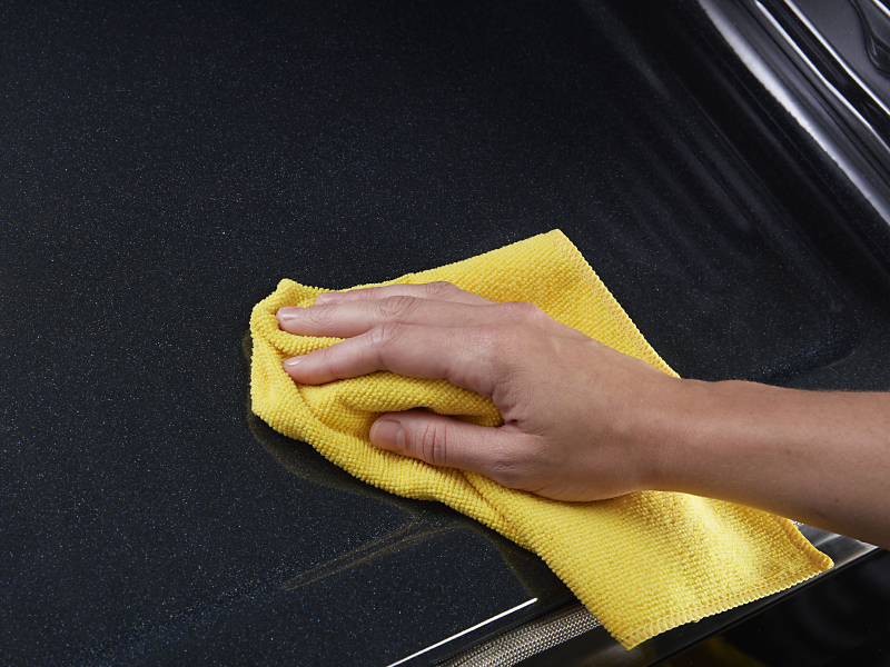 A person’s hand cleaning the interior of a Maytag® oven with a microfiber towel. 