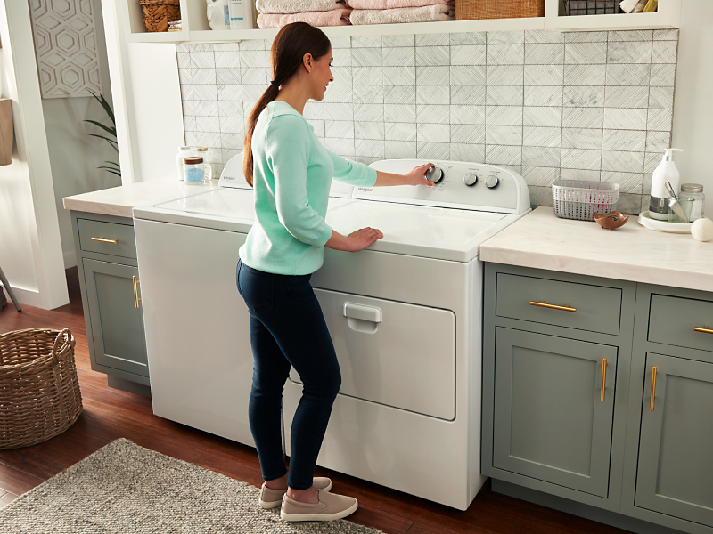 Woman selecting a cycle on a white Whirlpool® dryer