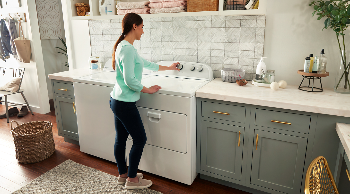 Woman selecting a cycle on a white Whirlpool® dryer