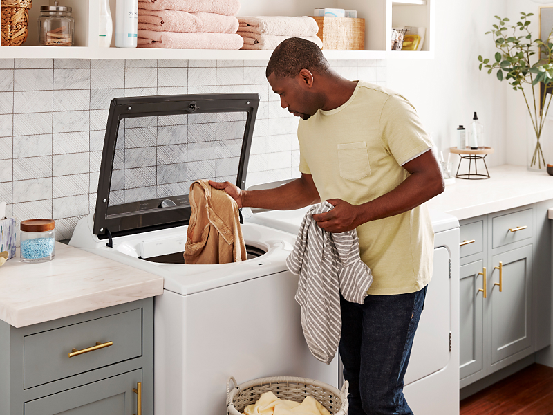 Person removing towels from a Whirlpool® top load washer