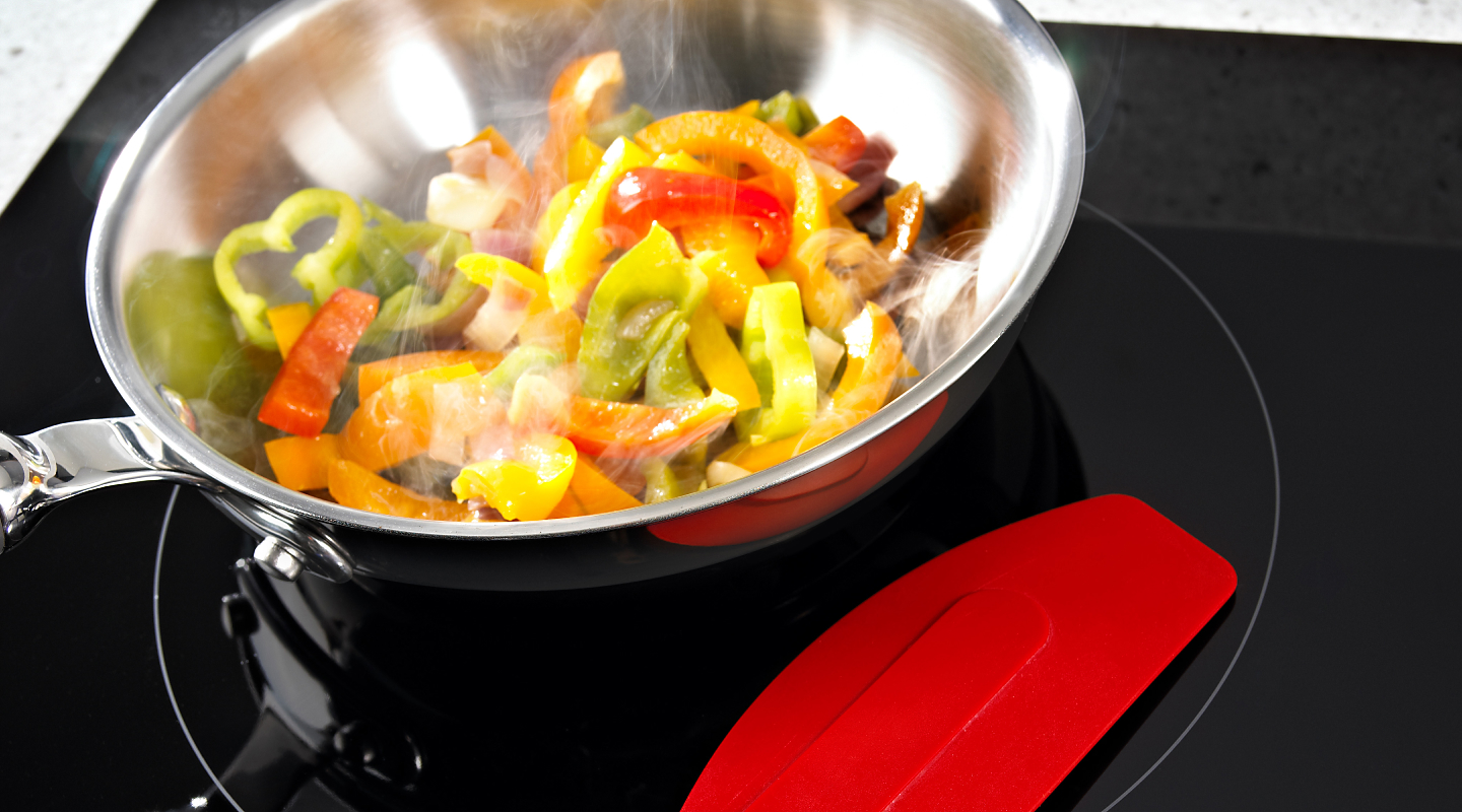 Bell peppers cooking in a pan on an electric cooktop