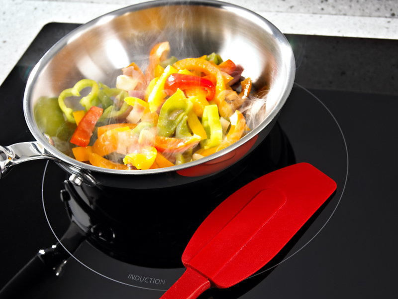 Bell peppers cooking in a pan on an electric cooktop