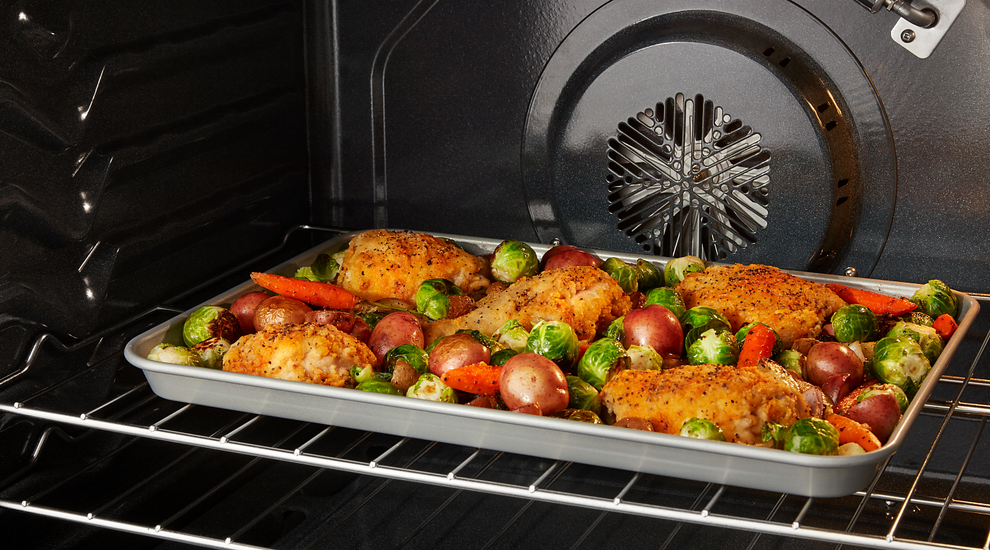 Chicken and vegetables roasting in a convection oven