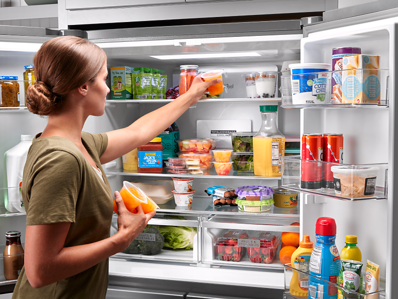 Person placing items on top shelf of Whirlpool® refrigerator