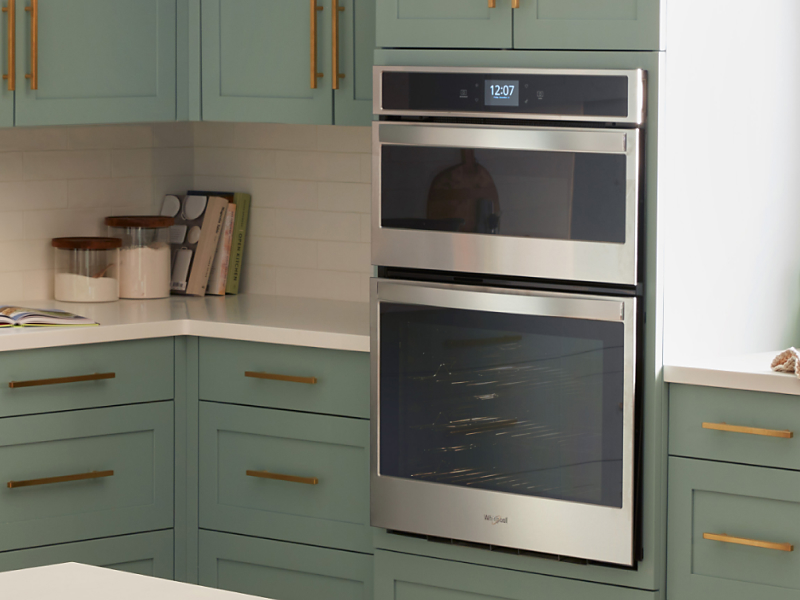 A double wall oven in a kitchen with green cabinetry