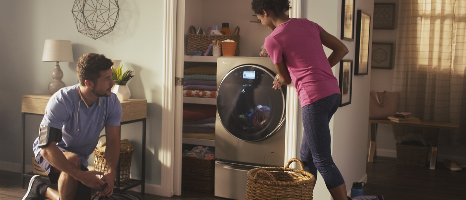 Man and woman in athletic gear loading the washing machine