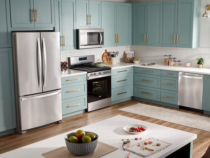 Stainless steel Whirlpool® appliances in a teal painted kitchen