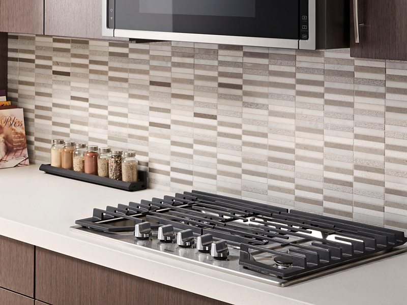 Whirlpool® gas cooktop in front of gray and white tile backsplash