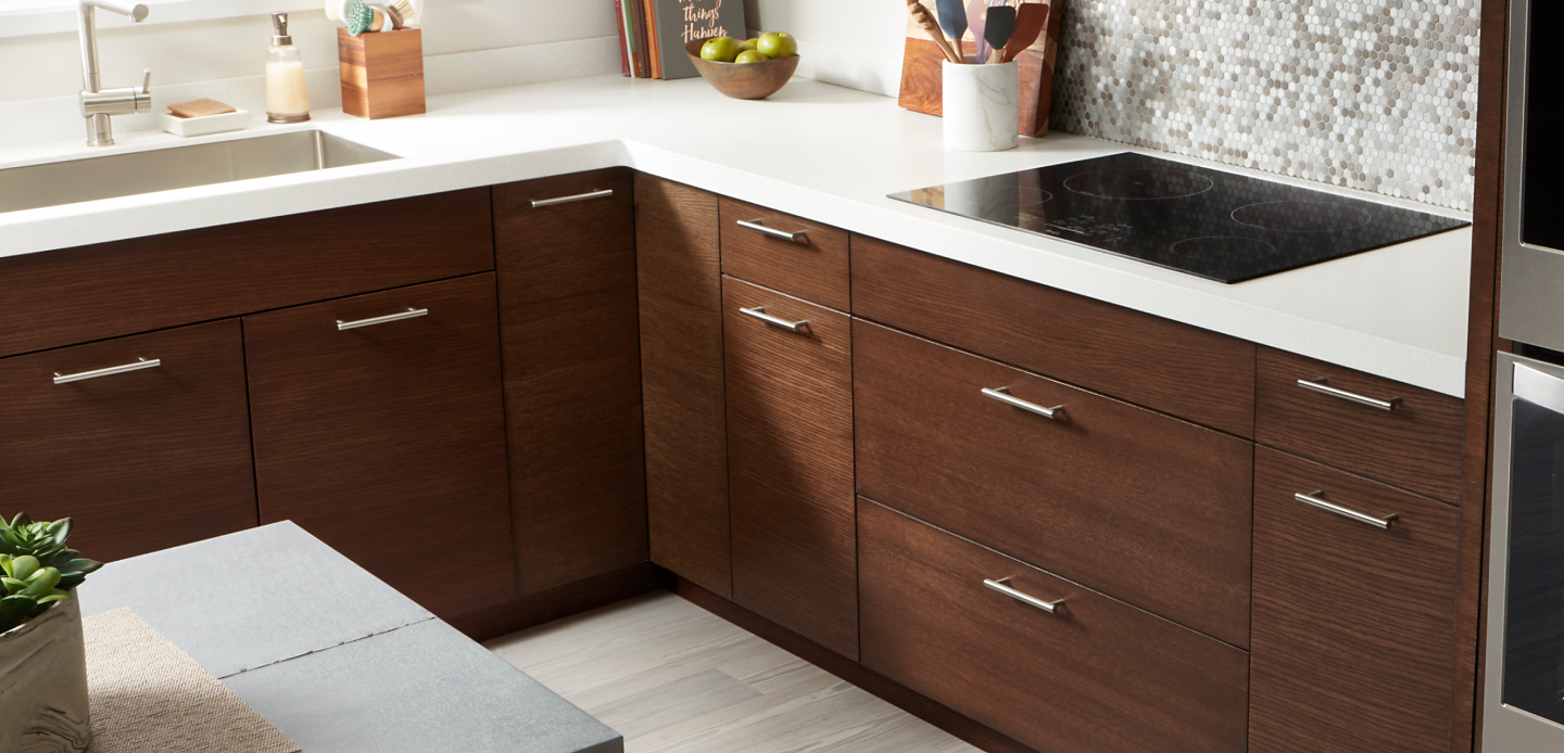 Whirlpool® electric cooktop and dark wooden cabinetry with white countertops