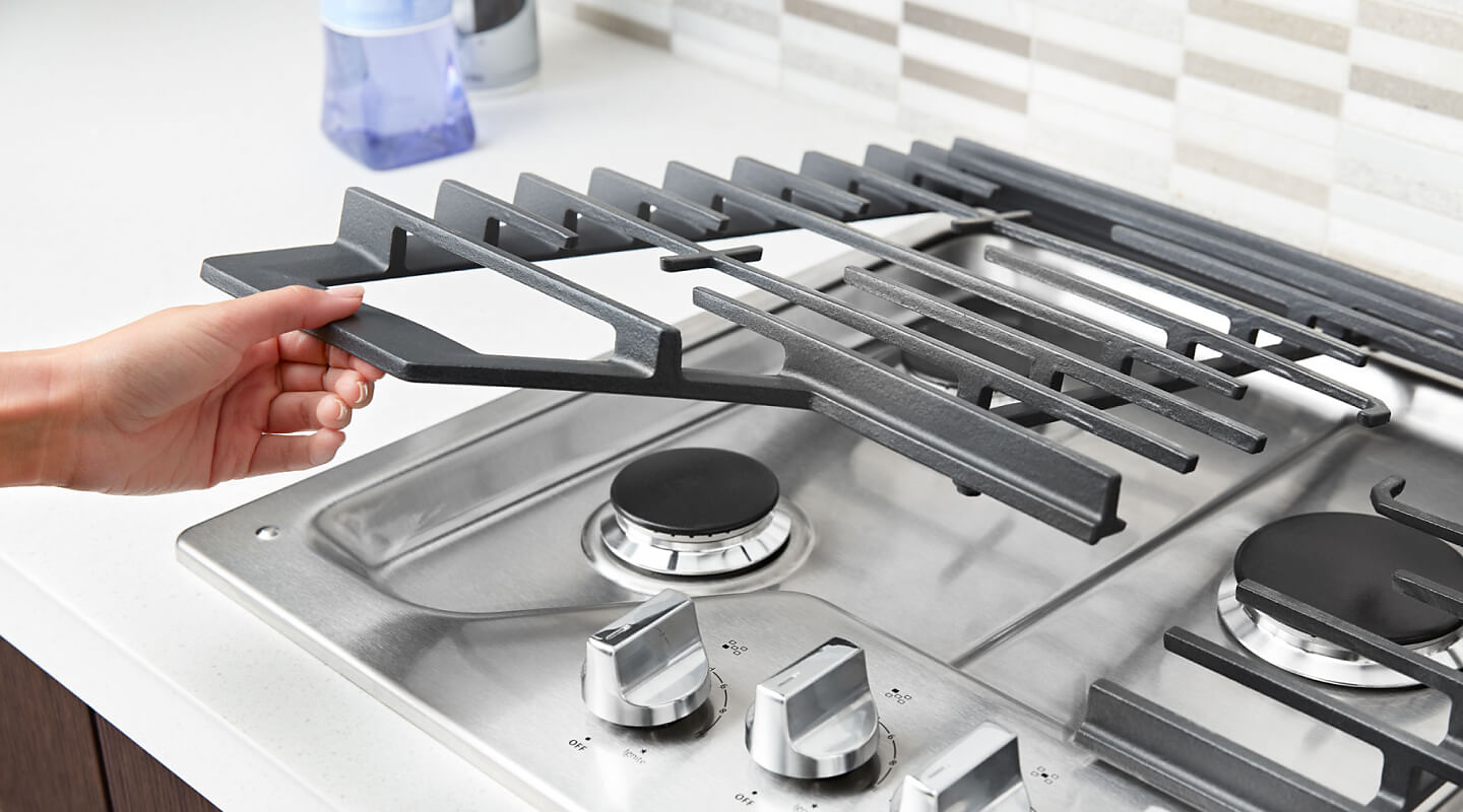 Person placing grates back on a gas cooktop