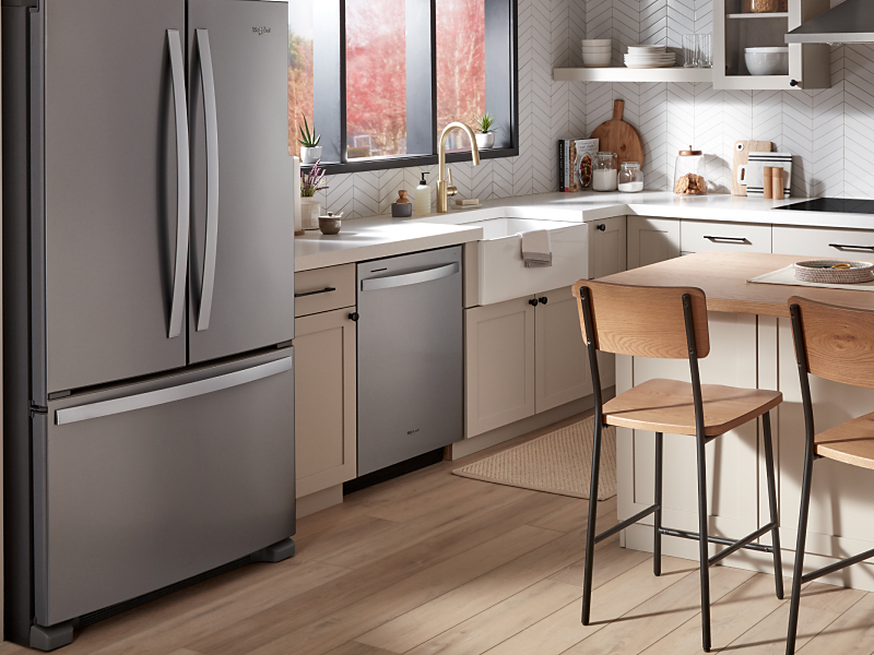 A Whirlpool® dishwasher and appliances in a kitchen with an island.