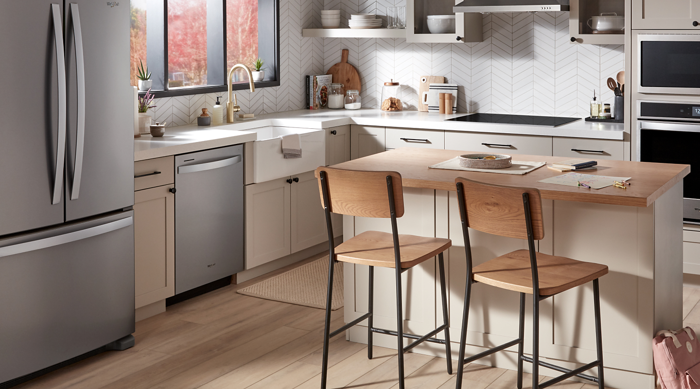 A Whirlpool® dishwasher and appliances in a kitchen with an island.
