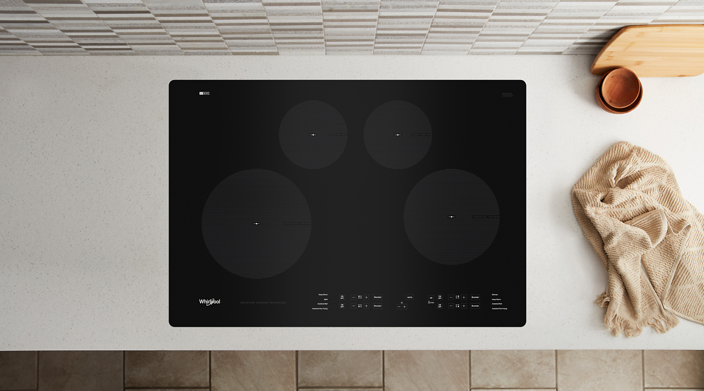 A black Whirlpool® cooktop next to various kitchen items