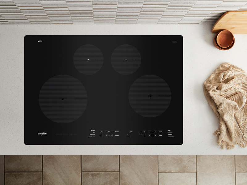 A black Whirlpool® cooktop next to various kitchen items