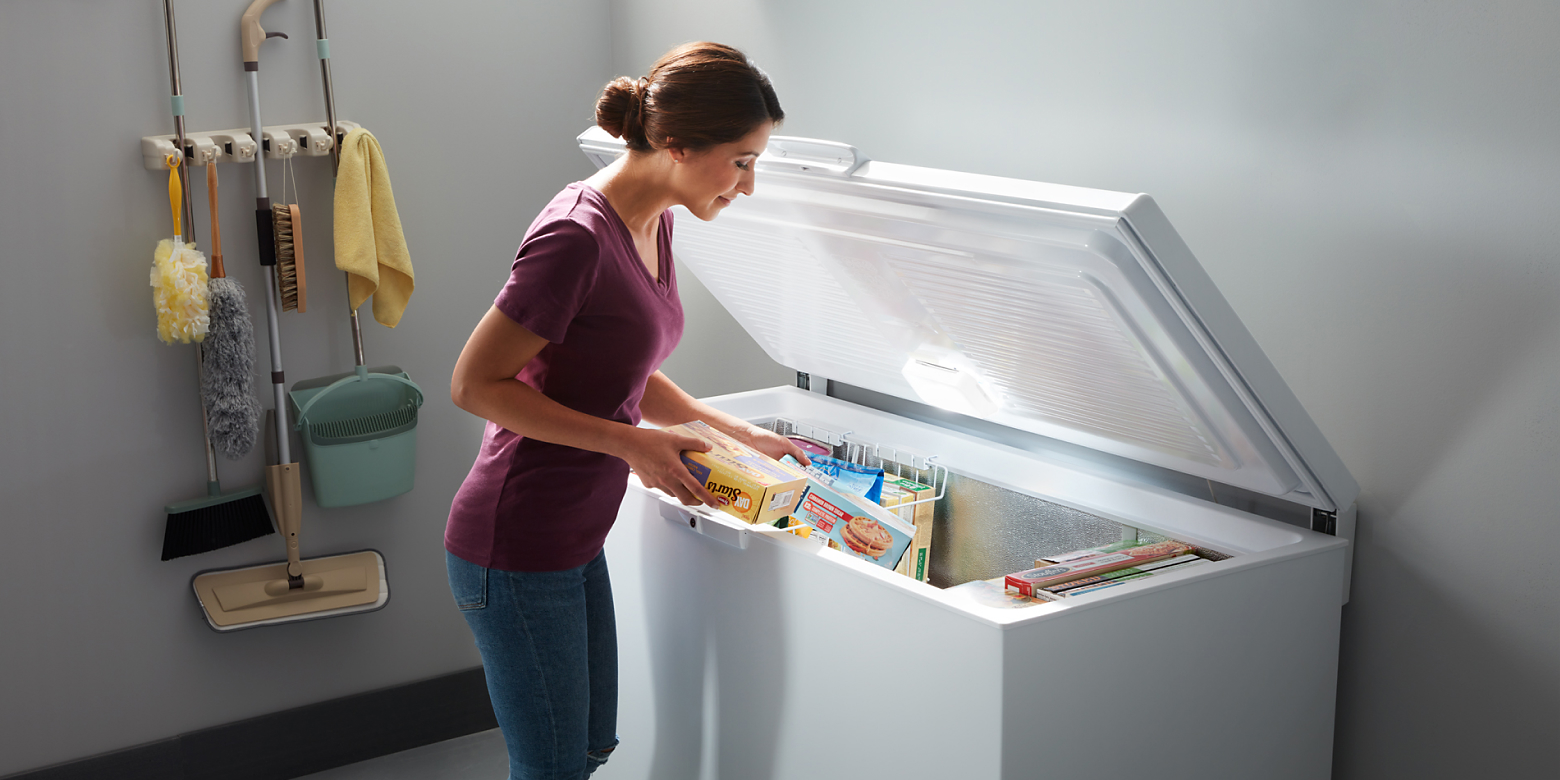Person placing food in garage-ready chest freezer