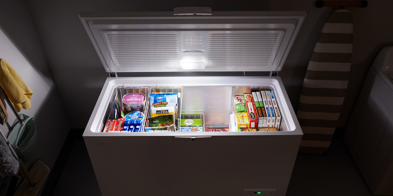 Chest freezer with food inside opened with light on