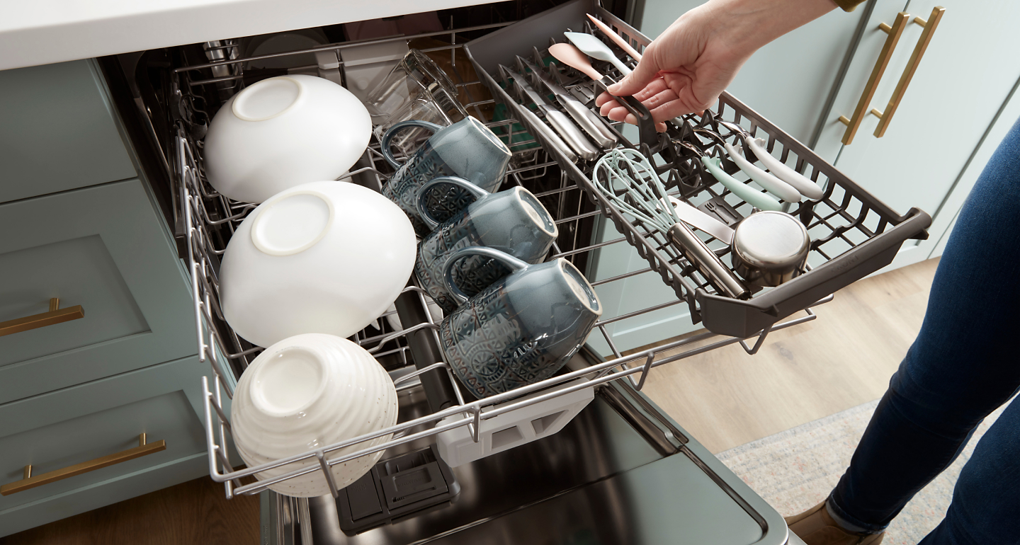 Silverware being placed on the third rack of a dishwasher