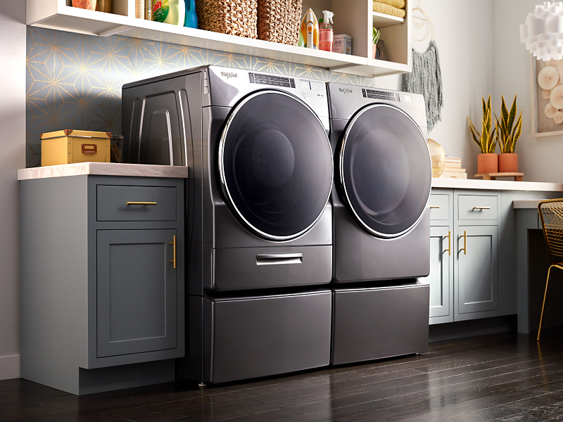 A gray front load Whirlpool® washer and dryer set in a modern laundry room