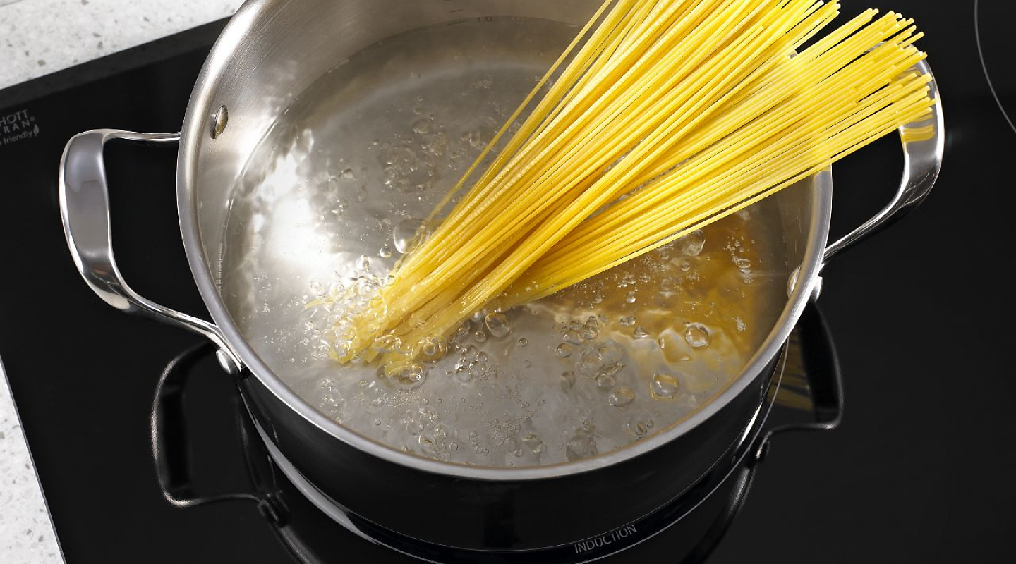 Spaghetti noodles in a pot of boiling water on an induction cooktop