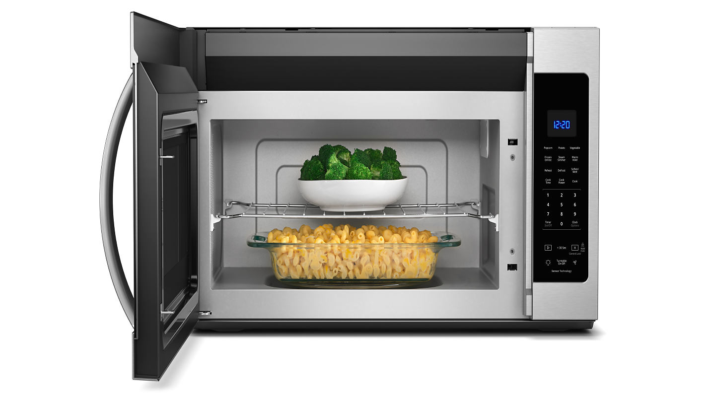 A stainless steel Whirlpool® over-the-range microwave with broccoli and macaroni and cheese inside