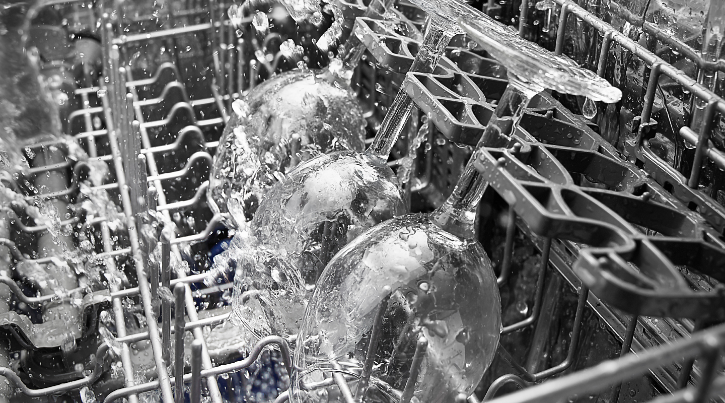 Wine glasses being sprayed in a dishwasher 