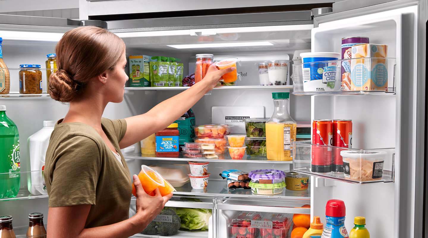 A person placing fruit in a fridge