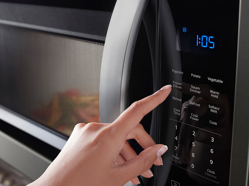 Person pressing button on a Whirlpool® microwave