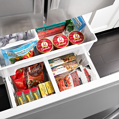 An open bottom freezer drawer holding a variety of frozen groceries