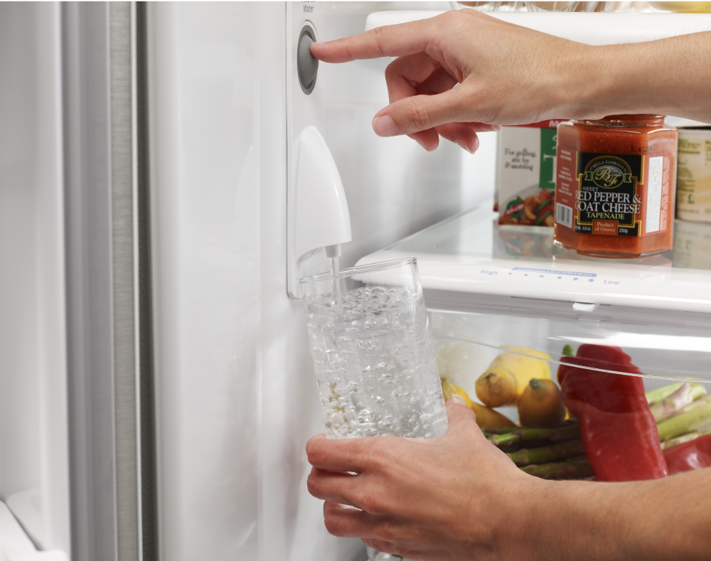 Filling a glass from an internal refrigerator water dispenser.