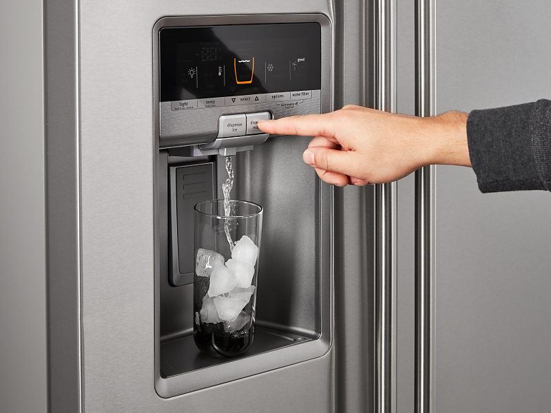 A person dispensing water out of a refrigerator ice maker