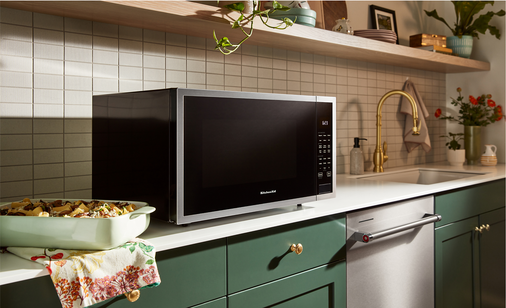 A countertop microwave with air fry function on a white countertop in a modern kitchen with green cabinetry. 